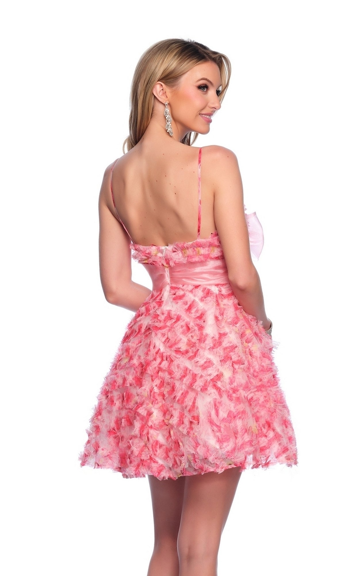 A woman wears the Dave and Johnny Short Pink Ruffle Hoco Dress 11769, featuring pink and white floral prints and spaghetti straps, as she stands facing away and glances over her shoulder against a white background.